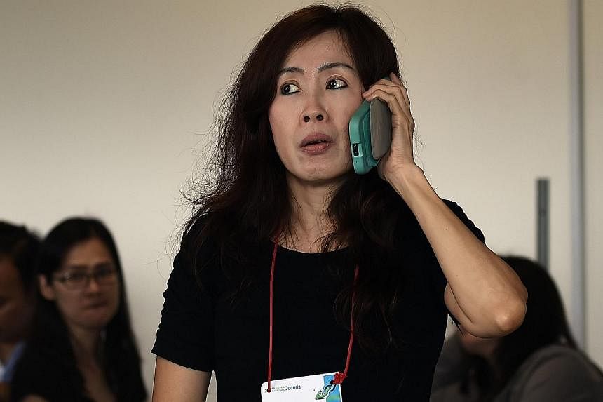 Family members of passengers onboard the missing Malaysian air carrier AirAsia flight QZ850, react to news of floating debris spotted in the search area, inside the crisis-centre set up at Juanda International Airport in Surabaya on Dec 30, 2014. -- 