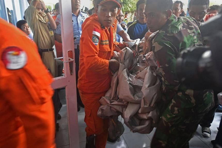 Members of the Indonesian air force carry items retrieved from the Java sea during search and rescue operations for the missing AirAsia flight QZ8501, in Pangkalan Bun, Central Kalimantan on Dec 30, 2014. -- PHOTO: AFP