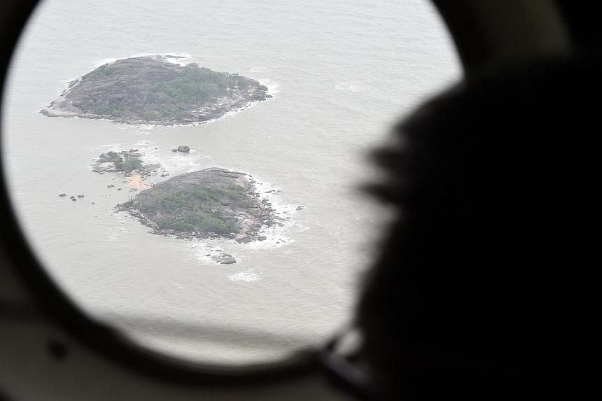 This picture shows a view through a window onboard a Republic of Singapore Air Force (RSAF) C-130 aircraft during the search and locate (SAL) operation for missing AirAsia flight QZ8501 over the Java sea on Dec 30, 2014. Recovery efforts were tempora