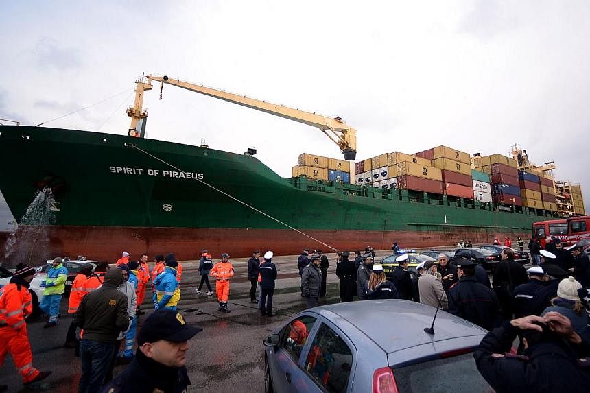 The Singapore-flagged cargo container ship Spirit of Piraeus, carrying 49 passengers evacuated from the ferry Norman Atlantic, arriving in the harbour of Bari on Dec 29, 2014, as Italian advanced rescue personnel and police wait on the quay. -- PHOTO