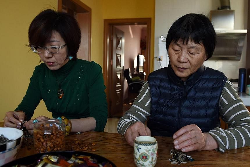 Relatives of passengers from the missing Malaysia Airlines flight MH370, Xu Jinghong (left) and Dai Shuqin sit at a table at Xu's home in Beijing on Dec 30, 2014. -- PHOTO: AFP