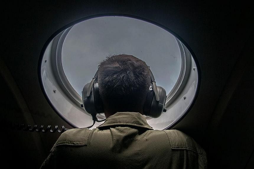 A member of the Indonesian military looks out of the window during a search and locate operation for missing Malaysian air carrier AirAsia flight QZ8501, over the waters of the Java Sea on Dec 29, 2014. -- PHOTO: AFP
