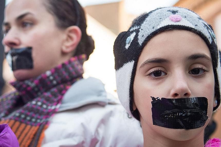 Demonstrators wearing tape over their mouths as they protest outside the Egyptian embassy in central London on Dec 29, 2014, to mark the one year anniversary of the arrest of three Al Jazeera journalists in Egypt. -- PHOTO: AFP