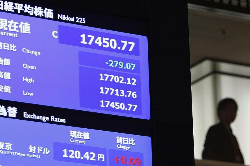 A man stands next to a stock quotation board displaying Japan's Nikkei average at the Tokyo Stock Exchange in Tokyo on Dec 30, 2014. -- PHOTO: REUTERS