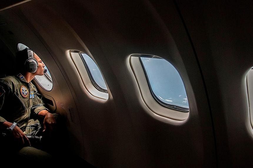 A member of the Indonesian military looks out of the window during the search operation for missing Malaysian air carrier AirAsia flight QZ8501 over the waters of the Java Sea on Dec 29, 2014. -- PHOTO: AFP