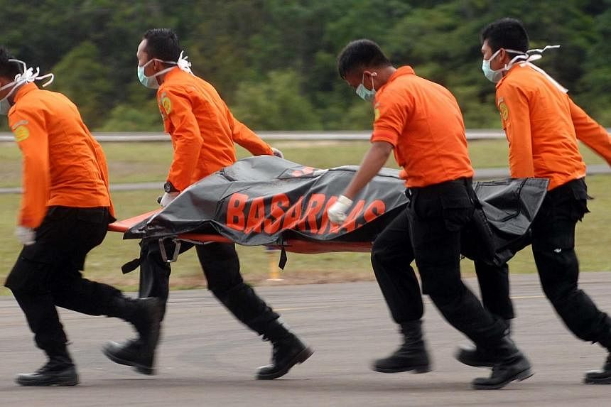 Members of an Indonesian search and rescue team carry a body on a stretcher during the recovery of victims who were on board the crashed AirAsia flight QZ8501 in Pangkalan Bun on Dec 31, 2014. -- PHOTO: AFP
