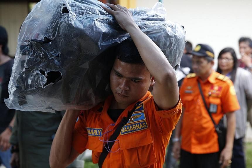 A search and rescue worker preparing to load body bags onto a flight to Kalimantan in Pangkal Pinang on Indonesia's Bangka island yesterday. As operations move to search and recovery, it would take weeks before the authorities and investigators are a