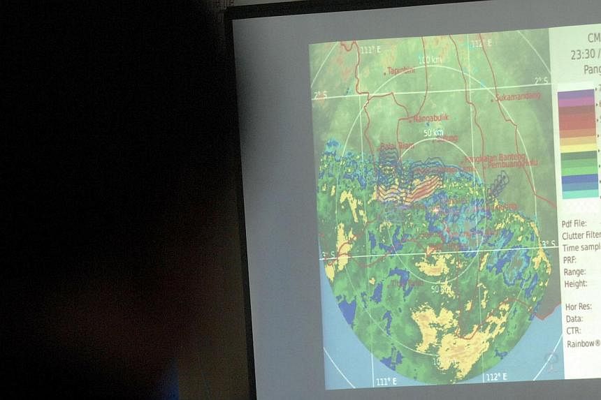 A man (left) monitors a weather map at Pangkalan Bun air base in Central Kalimantan on Dec 31, 2014, after the operation to find the missing Malaysian air carrier AirAsia flight QZ8501 was halted due to bad weather. -- PHOTO: AFP