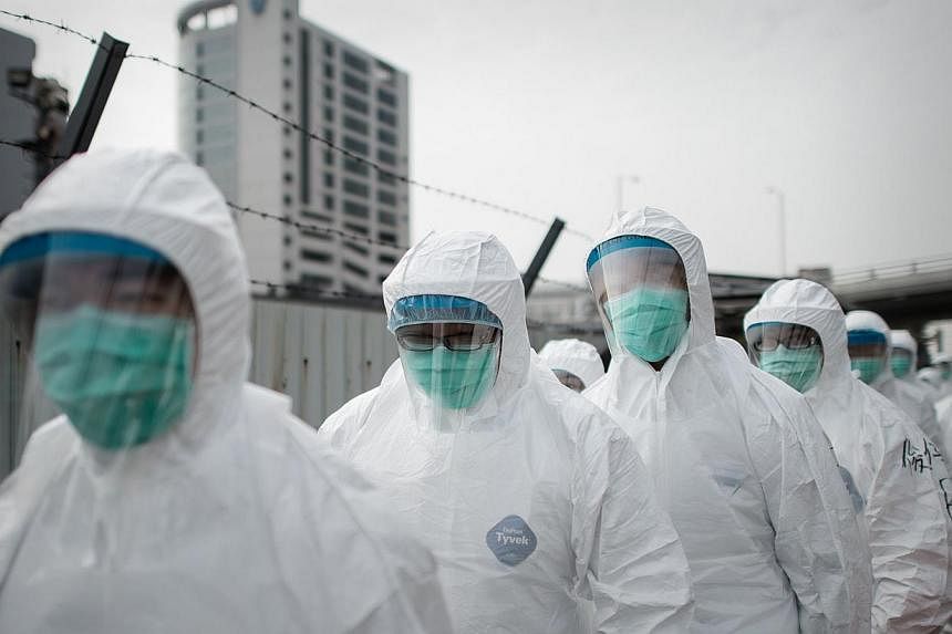A file picture taken Jan 28, 2014, shows officials wearing masks and protective suits ahead of a mass bird cull in Hong Kong.&nbsp;Hong Kong authorities said Wednesday they will cull 15,000 chickens after the deadly H7N9 virus was discovered in poult