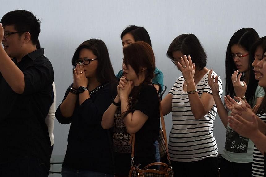 Family members of passengers onboard the plane pray inside a holding room at Juanda International Airport in Surabaya on Dec 31, 2014. -- PHOTO: AFP
