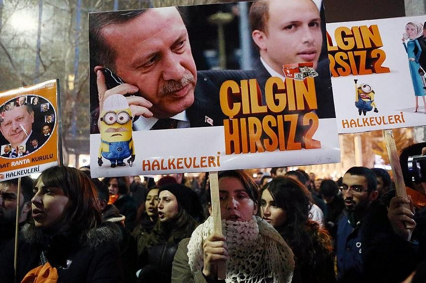 People hold placards with images of Turkish President Recep Tayyip Erdogan and his son Bilal Erdogan (centre right) that read "Crazy thief" as they protest against corruption in Ankara, on Dec 17, 2014. -- PHOTO: AFP