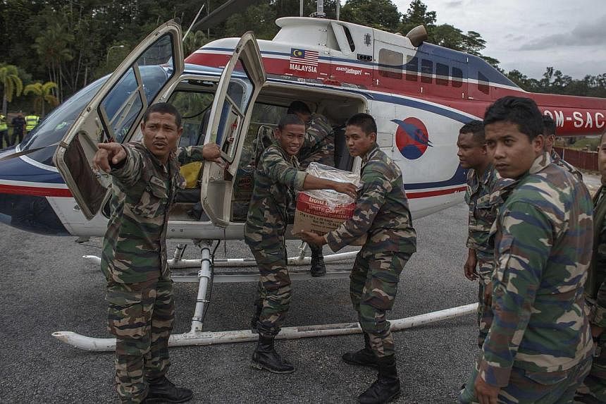 Malaysian soldiers carry relief supplies from a helicopter at Kuala Krai in Kelantan on Dec 30, 2014. -- PHOTO: REUTERS&nbsp;