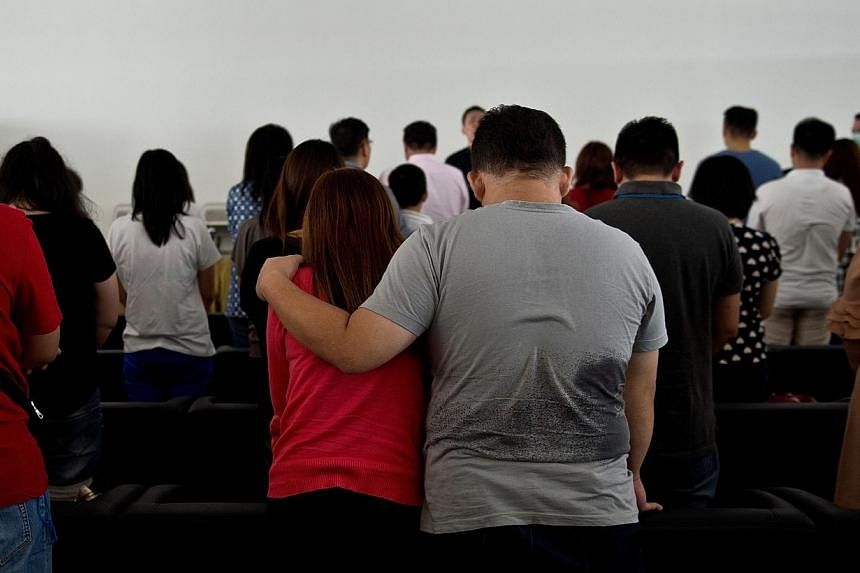 Family members of passengers onboard Malaysian air carrier AirAsia flight QZ8501 pray together inside a holding room at Juanda International Airport in Surabaya on Dec 31, 2014. -- PHOTO: AFP