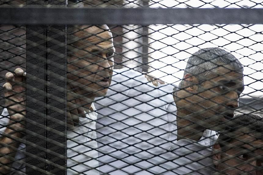 Al-Jazeera journalists Peter Greste (left), Mohamed Fadel Fahmy (centre) and Baher Mohamed listening to the verdict inside the defendants cage during their trial for allegedly supporting the Muslim Brotherhood,&nbsp;at the police institute near Cairo