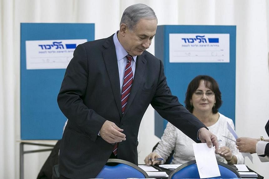 Israel's Prime Minister Benjamin Netanyahu (left) and his wife Sara (just seen, far right) cast their ballots for the Likud primary at a polling station in Jerusalem Dec 31, 2014. &nbsp;-- PHOTO: REUTERS