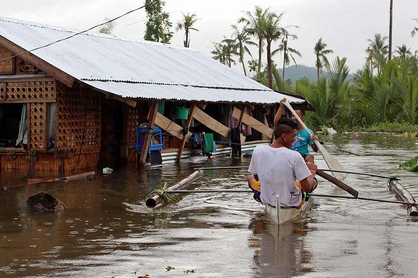 Residents paddle on a small boat to reach their homes in floodwaters in Palo town, Samar province on Dec 30, 2014. -- PHOTO: REUTERS&nbsp;