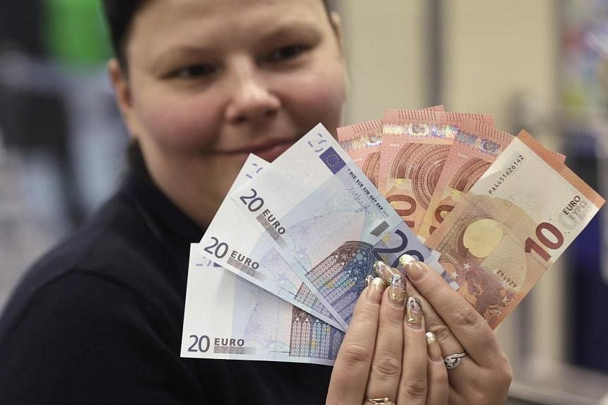 A cashier displaying euro banknotes before a shop opens in Vilnius, Lithuania, on Jan 1, 2015. The euro started the new year at 29-month lows in Asia after the head of the head of the European Central Bank fanned expectations it would take bolder ste