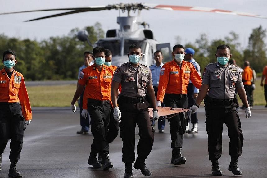Indonesian Search and Rescue and police carry a stretcher across the tarmac after receiving the remains of two passengers from AirAsia flight QZ8501 recovered from the sea at the airport in Pangkalan Bun, Central Kalimantan on Jan 2, 2015. -- PHOTO: 