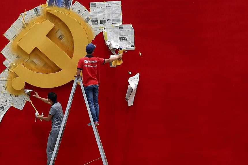 Workers peel newspaper off a wall after repainting the hammer and sickle symbol of the Chinese Communist Party flag on it at the Nanhu Revolutionary Memorial museum in Jiaxing, Zhejiang province, in this May 21, 2014, file photo. -- PHOTO: REUTERS