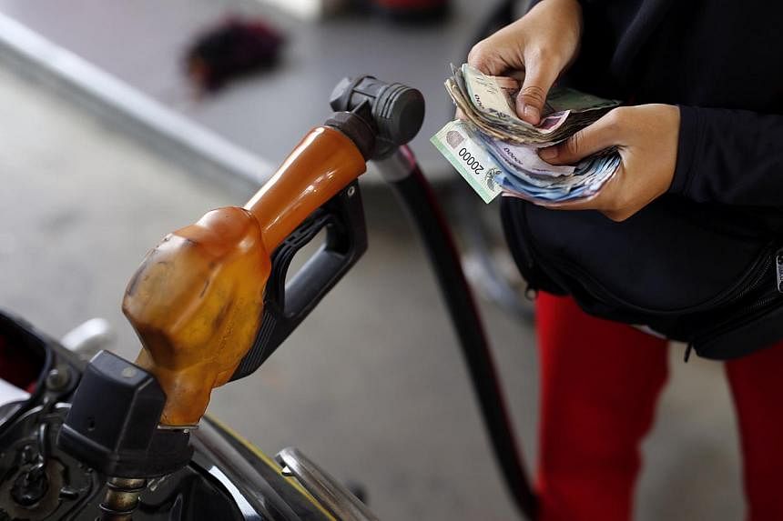 A worker at a state-owned Pertamina petrol station holds money as a motorcycle is filled with subsidised fuel in Jakarta on Oct 31, 2014. &nbsp;-- PHOTO: REUTERS
