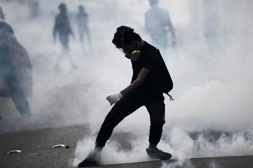 A Bahraini protester kicking back a tear gas canister during clashes with riot police following a protest against the arrest of the head of the banned Shi'ite opposition movement Al-Wefaq, Sheikh Ali Salman, on Jan 1, 2015 in Bilad al-Qadeem, a subur