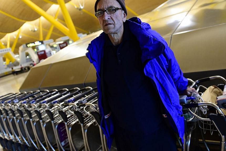 Bulgarian Valentin Giorgiev posing in front of luggage trolleys at Adolfo Suarez-Barajas airport's Terminal 4 in Madrid on Dec 30, 2014. A miniature community has sprung up among the terminal's residents, virtually all of them men. -- PHOTO: AFP