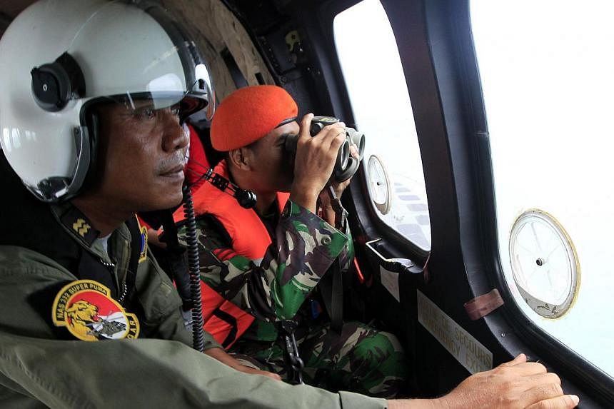 Indonesian crew members observing the surface of the sea during the search for AirAsia flight QZ8501 on board an aircraft over the Java Sea on Jan 1, 2015. -- PHOTO: AFP