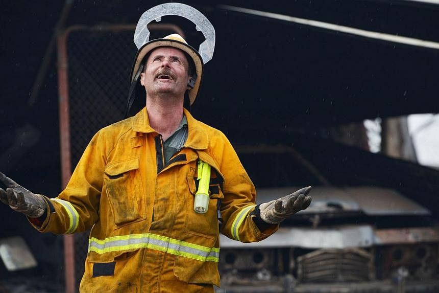 A Country Fire Service volunteer reacts as rain starts to fall near One Tree Hill in the Adelaide Hills, north-east of Adelaide on Jan 3, 2015. -- PHOTO: AFP