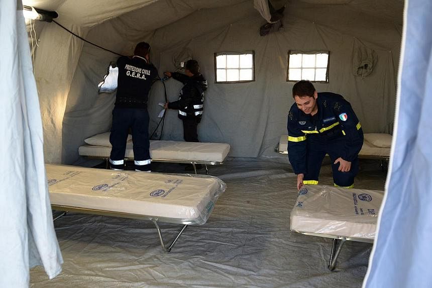 Italian Red Cross volunteers setting up a tent and camp beds to accommodate Syrian would-be immigants rescued from the Ezadeen ship being towed into Italy's Corigliano harbour on Jan 2, 2015.&nbsp;-- PHOTO: AFP