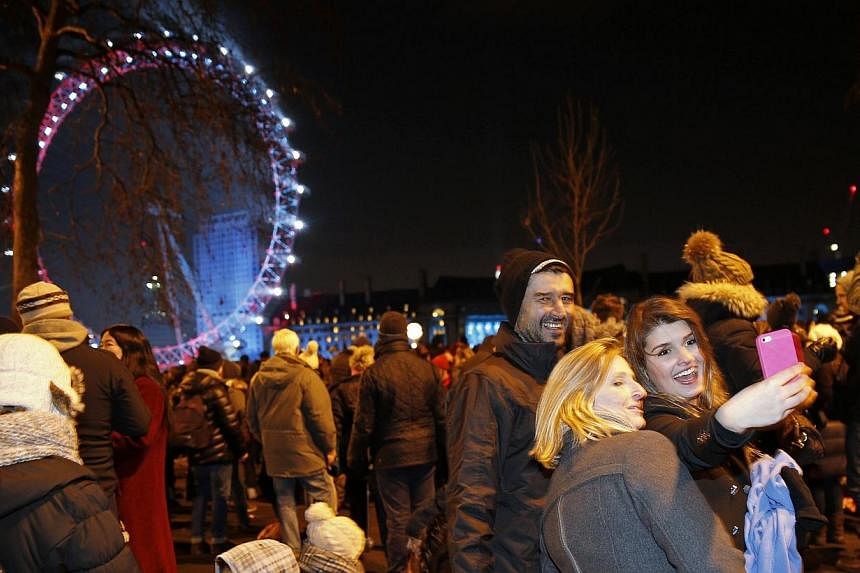 Revellers take a selfie as they wait for the fireworks to start at the London Eye on the River Thames during New Year's celebrations in London on Dec 31, 2014. -- PHOTO: REUTERS