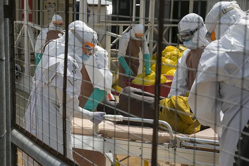 British health workers lift a newly admitted Ebola patient onto a wheeled stretcher in to the Kerry town Ebola treatment centre outside Freetown on Dec 22, 2014.&nbsp;Ending the deadliest Ebola outbreak in history is "within our reach", the UN's new 
