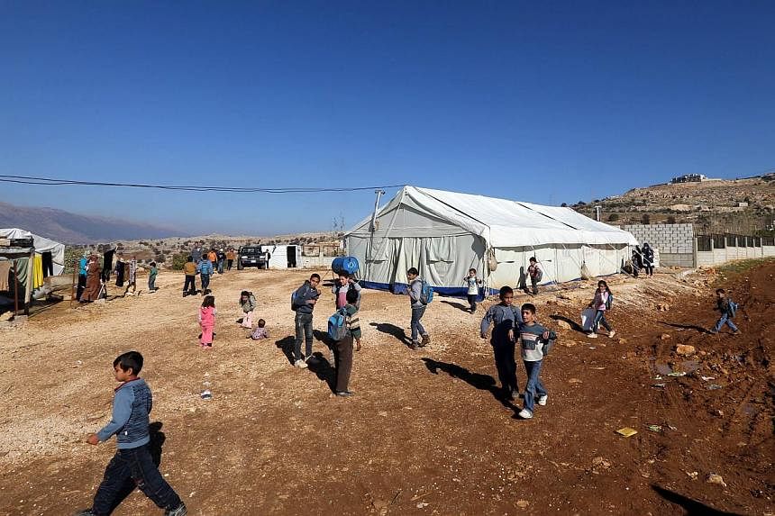 Syrian refugee children walk outside a tent being used as a school at a Syrian refugees camp in the village of Baaloul, in the west of Lebanon's Bekaa Valley on Dec 16, 2014.&nbsp;Lebanon is to impose visa restrictions on Syrians for the first time a