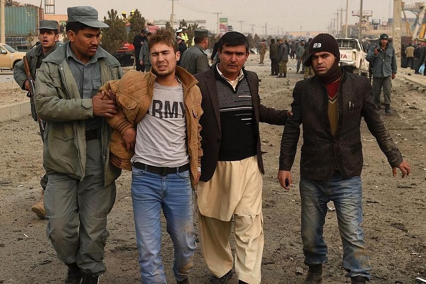 A wounded Afghan youth (2nd from left) receives assistance at the scene of a suicide attack on a European Union police vehicle along the Kabul-Jalalabad road in Kabul on Jan 5, 2015.&nbsp;The suicide car bombing killed at least one passer-by but did 