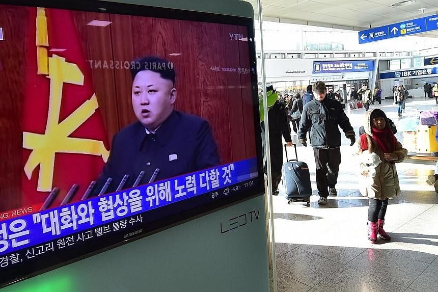 Travellers walk past a television screen showing North Korean leader Kim Jong Un's New Year speech, at a railroad station in Seoul on Jan 1, 2015.&nbsp;China on Jan 5 called on "relevant parties" to avoid action that would escalate tension on the Kor