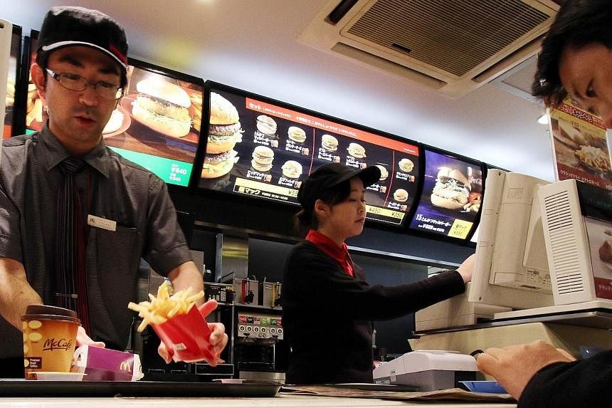 An employee serves french fries to a customer at a McDonald's restaurant in Tokyo on Dec 16, 2014.&nbsp;McDonald's Japan said Monday it was facing more chicken nugget woes after a customer found a piece of vinyl inside the popular menu item. -- PHOTO