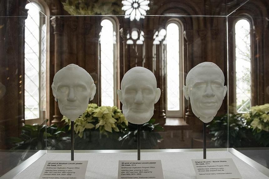Three-D prints of a 3-D scan of former President Abraham Lincoln's life masks (left, centre) are seen with a print of a live 3-D scan of US President Barack Obama at the Smithsonian on Dec 4, 2014 in Washington, DC. -- PHOTO: AFP