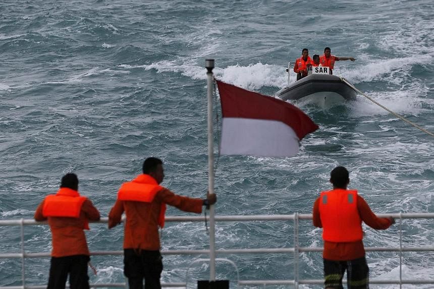 Rescue team members in a boat communicate with other members of the team on the deck of the Search and Rescue (SAR) ship KN Purworejo during a search operation for passengers onboard AirAsia Flight QZ8501 in the Java Sea on Jan 4, 2015. -- PHOTO: REU