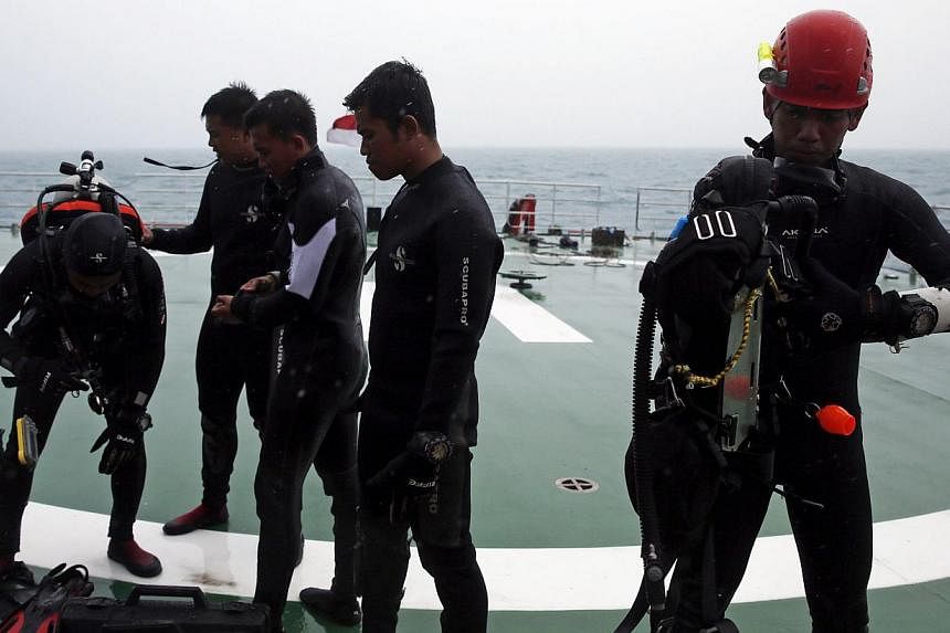 A group of divers preparing their gear on the deck of the ship KN Purworejo during a search operation for passengers onboard AirAsia Flight QZ8501 in the Java Sea on Jan 4, 2015. -- PHOTO: REUTERS