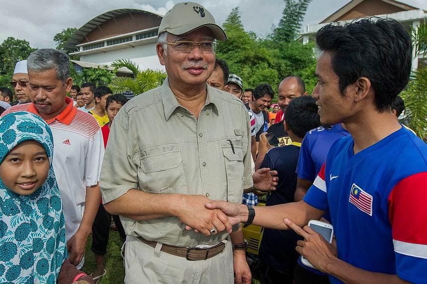 Flood victims greeting Malaysian Prime Minister Najib Razak (centre) as he arrives at an evacuation center in Pasir Mas, on the outskirts of Kota Bharu, on Dec 27, 2014. -- PHOTO: AFP