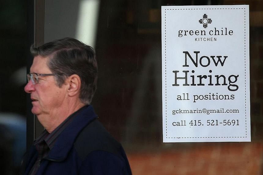 A pedestrian walks past a "now hiring" sign posted on the window of a shop on Nov 7, 2014 in San Rafael, California. Last year, the U.S. economy recovered all of the jobs lost during the Great Recession and more. -- PHOTO: AFP