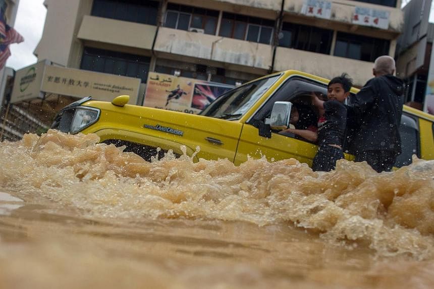 A vehicle ploughing through flood waters in Kota Baru last month. Natural disasters are likely to feature again as global warming gets worse. The new year will also bring economic challenges for Malaysia as the US economy recovers and investors pull 