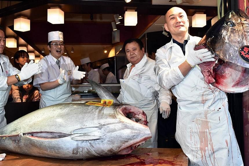 Mr Kiyoshi Kimura (second from right), president of the firm behind Sushi-Zanmai restaurant chain, cut the 180.4kg bluefin tuna at his main restaurant near Tokyo's Tsukiji fish market yesterday. Increasing pressure has been put on Japan to reduce con