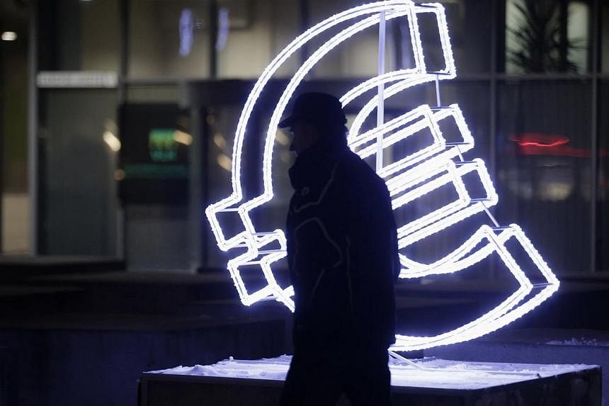 A man walking past a euro sign in Vilnius, Lithuania, on Dec 31, 2014. A falling euro is good news for Singaporeans planning to visit Europe this year but economists say the impact on Singapore's economy is more mixed. -- PHOTO: REUTERS&nbsp;
