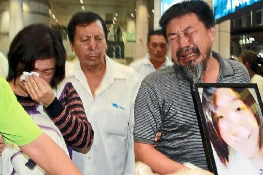 The deceased's father, Tan Chin Hin, hugging a portrait of his only daughter while exiting the arrival hall, followed by his sobbing wife, Ms Lee Siew Yan,and two sons on Monday. -- PHOTO: THE STAR / ASIA NEWS NETWORK