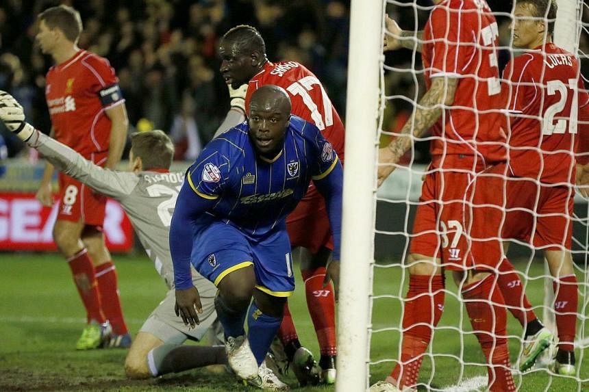 AFC Wimbledon's Adebayo Akinfenwa (centre) celebrates after scoring during the FA Cup third round soccer match against Liverpool at Kingsmeadow Stadium in Kingston-upon-Thames, southern England on Jan 5, 2015. -- PHOTO: REUTERS