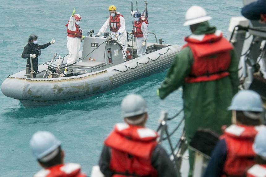 Recovery team from the the USS Sampson signalling the boat deck crew while conducting search and recovery operations in support of the Indonesian-led AirAsia flight QZ8501 search efforts in the Java Sea. An Indonesian official said on Wednesday that 