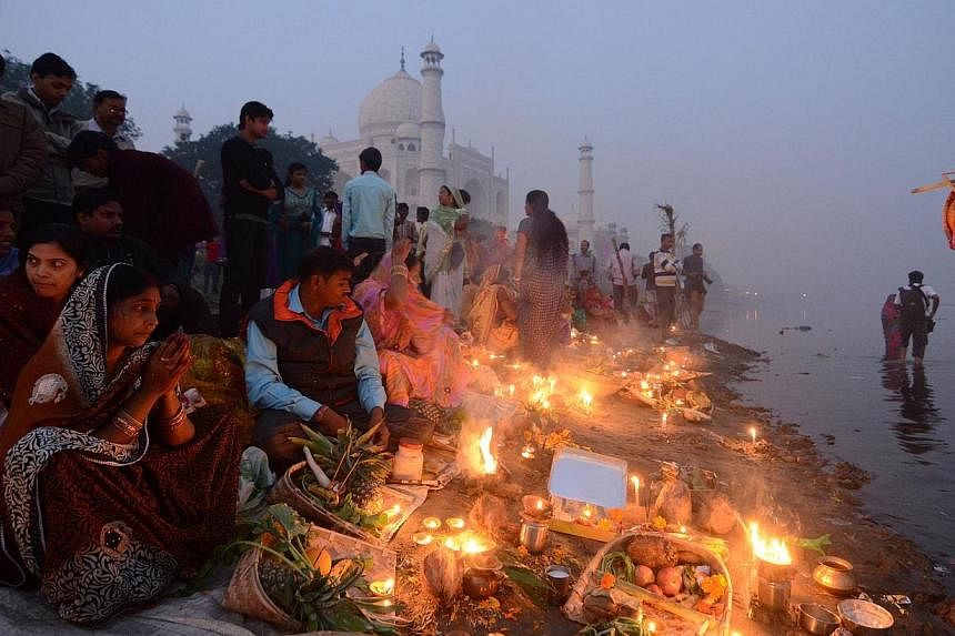 Indian Hindu devotees offer prayers on the banks of the Yamuna river as the landmark Taj Mahal monument is seen in the background during daybreak in Agra on Oct 30, 2014.&nbsp;A lawmaker from India's ruling party has called for Hindu women to have at