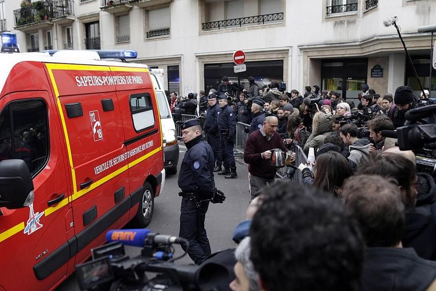 Firefighters and policemen are surrounded by journalists outside of the headquarters of the French satirical newspaper Charlie Hebdo in Paris on Jan 7, 2015, after armed gunmen stormed the offices leaving twekve dead.&nbsp;French civic groups and jou