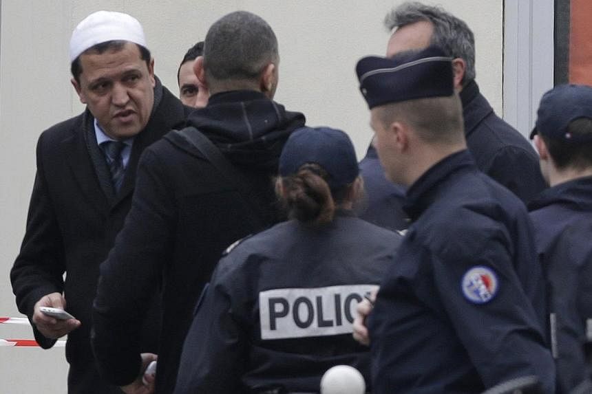 Hassen Chalghoumi (left), Imam of the municipal Drancy mosque in Seine-Saint-Denis, walks with police near the Paris offices of Charlie Hebdo, a satirical newspaper, after a shooting Jan 7, 2015. -- PHOTO: REUTERS