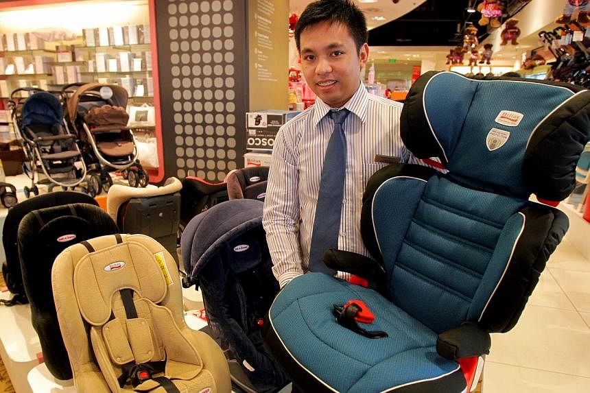A sales advisor shows a child seat at Robinsons in 2012. Under Singapore law, failing to comply with child-seat regulations can incur a fine of up to $1,000 or jail of up to three months. -- PHOTO: THE NEW PAPER&nbsp;